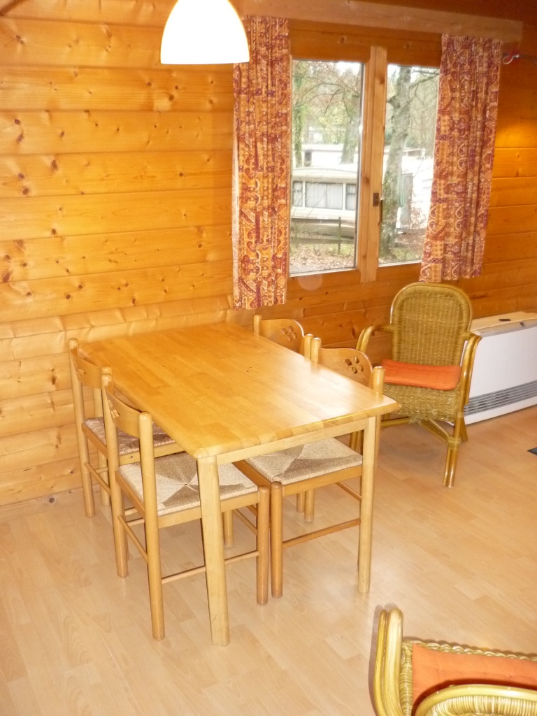 De volledig ingerichte woonkeuken is voorzien van een houten tafel met vier stoelen en twee fauteuils.